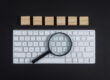 Vergrootglas op toetsenbord als symbool voor SEO content analyse en Google beoordeling.