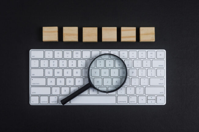 Vergrootglas op toetsenbord als symbool voor SEO content analyse en Google beoordeling.