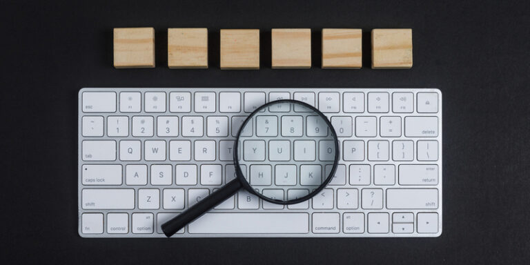 Vergrootglas op toetsenbord als symbool voor SEO content analyse en Google beoordeling.